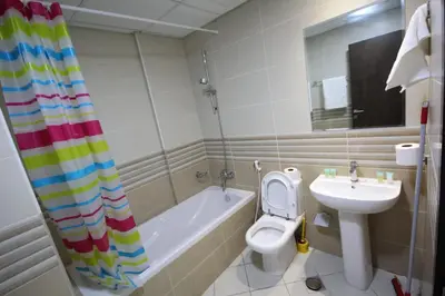 a bathroom with a toilet and a tub and a sink at Cozy Rooms and Small Partitions for Men guests in Dubai in Dubai