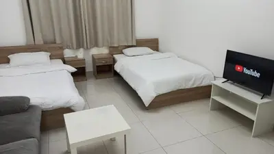 a hotel room with two beds and a flat screen tv at Cozy Rooms and Small Partitions for Men guests in Dubai in Dubai