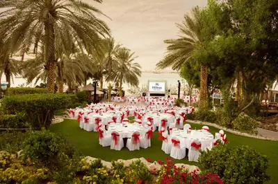 a group of tables with white chairs in a park at Hilton Dubai Jumeirah in Dubai