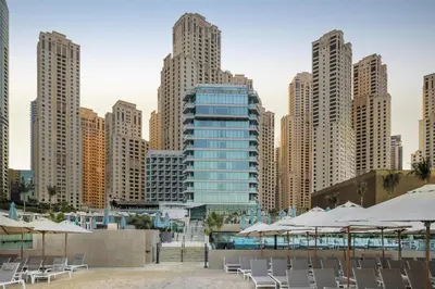 a group of chairs and umbrellas in front of a city at Hilton Dubai Jumeirah in Dubai