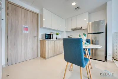 a kitchen with a table and a blue chair at Spotless 1BR at UNA Town Square Dubailand by Deluxe Holiday Homes in Dubai