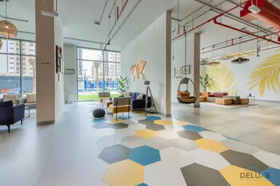 a large room with a lobby with a geometric floor at Spotless 1BR at UNA Town Square Dubailand by Deluxe Holiday Homes in Dubai