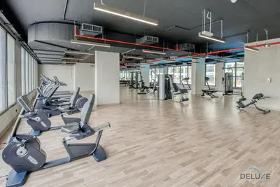 a gym with treadmills and elliptical machines at Spotless 1BR at UNA Town Square Dubailand by Deluxe Holiday Homes in Dubai
