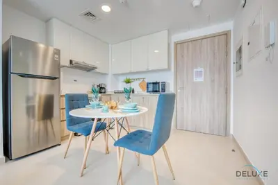 a kitchen with a table and chairs and a refrigerator at Charismatic 1BR at UNA Town Square Dubailand by Deluxe Holiday Homes in Dubai