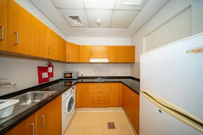 a small kitchen with wooden cabinets and a sink at City Stay Grand Hotel Apartments - Al Barsha in Dubai
