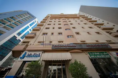 a tall building with a city stay group sign on it at City Stay Grand Hotel Apartments - Al Barsha in Dubai