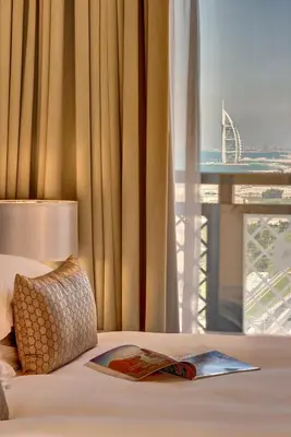 a bed with a magazine on it with a window at Arjaan by Rotana - Dubai Media City in Dubai