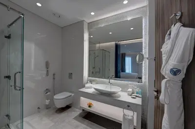 a bathroom with a sink and a toilet and a mirror at Arjaan by Rotana - Dubai Media City in Dubai
