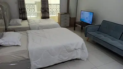 a room with two beds and a couch and a television at Budget Rental Studio Apartments in Dubai in Dubai
