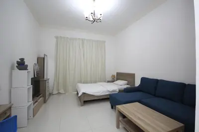 a living room with a blue couch and a bed at Budget Rental Studio Apartments in Dubai in Dubai