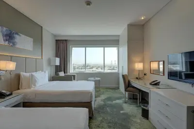a hotel room with two beds and a desk at Millennium Lakeview Hotel in Dubai