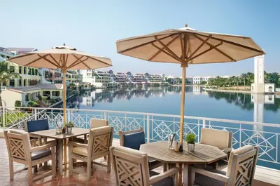 two tables and umbrellas on a balcony with a river at Millennium Lakeview Residences in Dubai