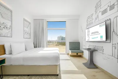 a white room with a bed and a tv at Ecos Dubai Hotel at Al Furjan in Dubai