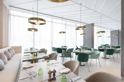 a restaurant with white tables and green chairs at Ecos Dubai Hotel at Al Furjan in Dubai