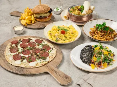a table topped with plates of food and different foods at Ecos Dubai Hotel at Al Furjan in Dubai