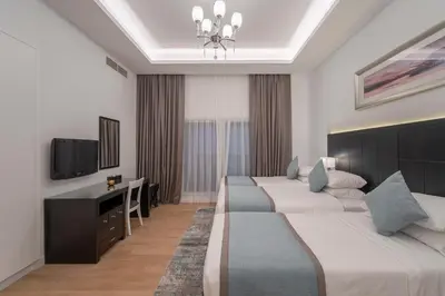 a hotel room with three beds and a television at Rose Garden Hotel Apartments - Al Barsha, Near Metro Station in Dubai