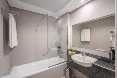a white bathroom with a sink and a shower at Rose Garden Hotel Apartments - Al Barsha, Near Metro Station in Dubai