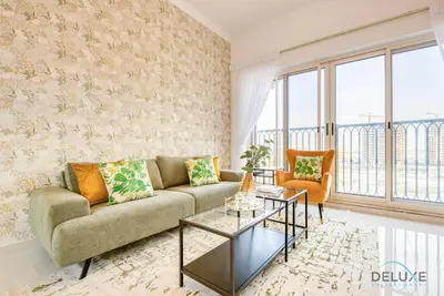 a living room with a couch and a table at Sunny 1BR at Canal Residences West Dubai Sports City by Deluxe Holiday Homes in Dubai