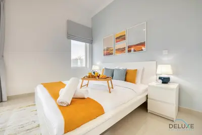 a white bedroom with a bed with a table on it at Sunny 1BR at Canal Residences West Dubai Sports City by Deluxe Holiday Homes in Dubai