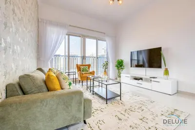 a living room with a couch and a tv at Sunny 1BR at Canal Residences West Dubai Sports City by Deluxe Holiday Homes in Dubai