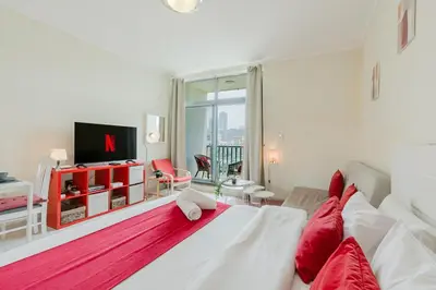 a bedroom with a large white bed with red pillows at RH - Beautiful canal view, Sleek & spacious Studio, central location in Dubai