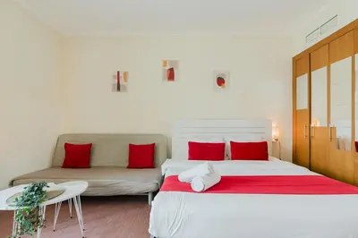 a bedroom with a bed and a couch with red pillows at RH - Beautiful canal view, Sleek & spacious Studio, central location in Dubai
