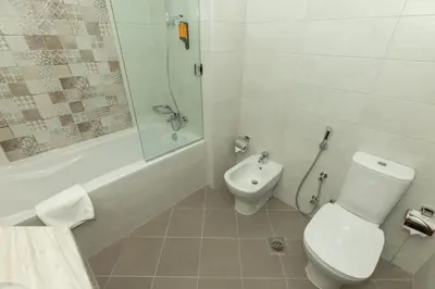a bathroom with a toilet and a tub and a sink at Grand Stay Holiday Homes Rental in Dubai