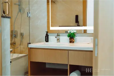 a bathroom with a sink and a mirror and a shower at HE Hotel Apartments in Dubai