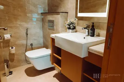 a bathroom with a white sink and a toilet at HE Hotel Apartments in Dubai
