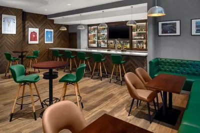 a bar with green chairs and tables in a restaurant at Holiday Inn Express Dubai, Jumeirah by IHG in Dubai