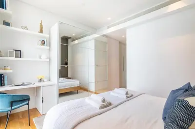 a white bedroom with a bed and a desk at GuestReady - The Best Bluewaters View in Dubai