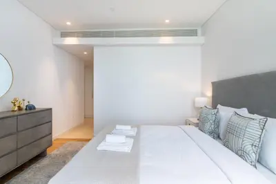a bedroom with a large white bed and a mirror at GuestReady - The Best Bluewaters View in Dubai