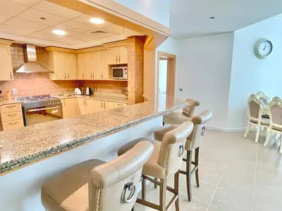 a kitchen with a bar with chairs and a counter at Luxury - Beachfront - Spacious Shoreline residences - 5 star private beach resort in Dubai