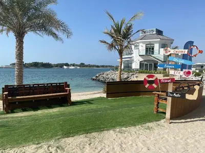 a house on the beach with two benches and palm trees at Luxury - Beachfront - Spacious Shoreline residences - 5 star private beach resort in Dubai