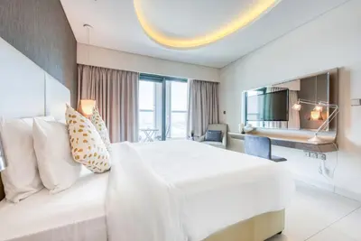 a hotel room with a large white bed and a desk at Maison Privee - Cool Dubai Apt next Burj Khalifa & Design District in Dubai