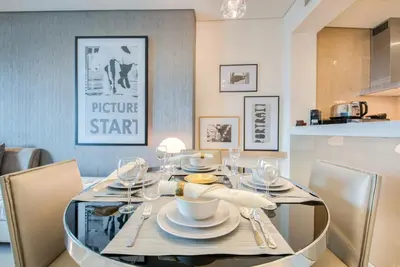 a dining room with a glass table and chairs at Maison Privee - Cool Dubai Apt next Burj Khalifa & Design District in Dubai