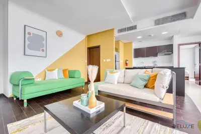 a living room with a couch and a table at Homely 1BR at The Matrix Dubai Sports City by Deluxe Holiday Homes in Dubai
