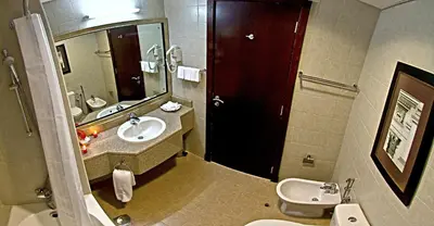 a bathroom with a sink and a toilet and a mirror at Chelsea Gardens Hotel Apartment in Dubai