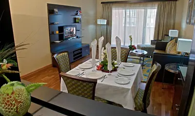a room with a table and chairs and a living room at Chelsea Gardens Hotel Apartment in Dubai
