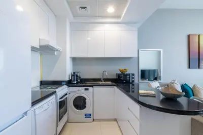 a kitchen with white cabinets and a washer and dryer at The Smart Concierge - Damac 108 in Dubai