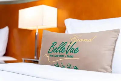 a bed with a pillow with the words grand belize on it at Belle Vue Building in Dubai
