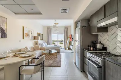 a kitchen and living room with a table and chairs at GuestReady Holiday Homes - A Rose in the Sky in Dubai