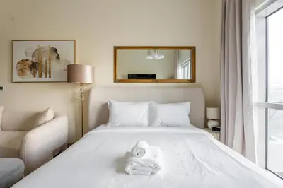 a bedroom with a white bed with a stuffed animal on it at GuestReady Holiday Homes - A Rose in the Sky in Dubai