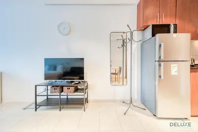 a kitchen with a refrigerator and a table at Calm Studio at Lake View Tower JLT by Deluxe Holiday Homes in Dubai