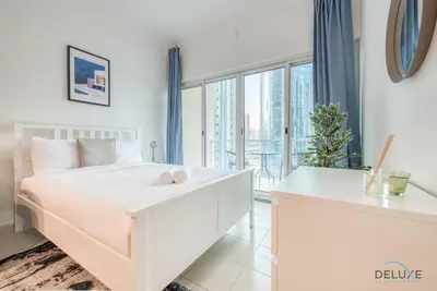 a white bedroom with a white bed and a large window at Calm Studio at Lake View Tower JLT by Deluxe Holiday Homes in Dubai
