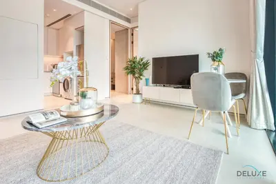 a living room with a table and a chair and a television at Exquisite 1BR at The Address Residences in JBR by Deluxe Holiday Homes in Dubai