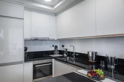a kitchen with white cabinets and a bowl of fruit on the counter at Royal Club By RVHR, Noora Tower, Al Habtoor City, Business Bay in Dubai
