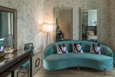 a living room with a blue couch and a mirror at Royal Club By RVHR, Noora Tower, Al Habtoor City, Business Bay in Dubai