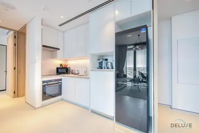 a kitchen with white cabinets and a glass wall at Classy 1BR at The Address Residences in JBR by Deluxe Holiday Homes in Dubai