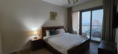 a bedroom with a bed and a large window at Cozy 2 BR apt Golf Tower Greens, stunning Golf views in Dubai